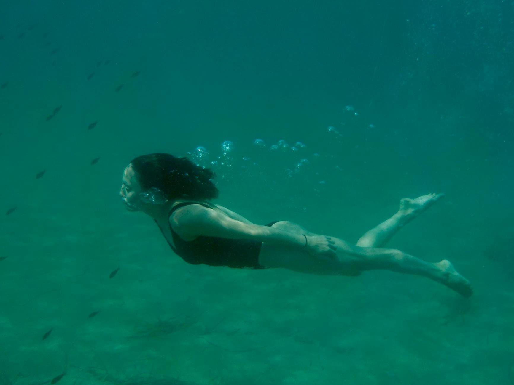 Kobieta płynie pod wodą wśród bąbelków podczas zimnej kąpieli