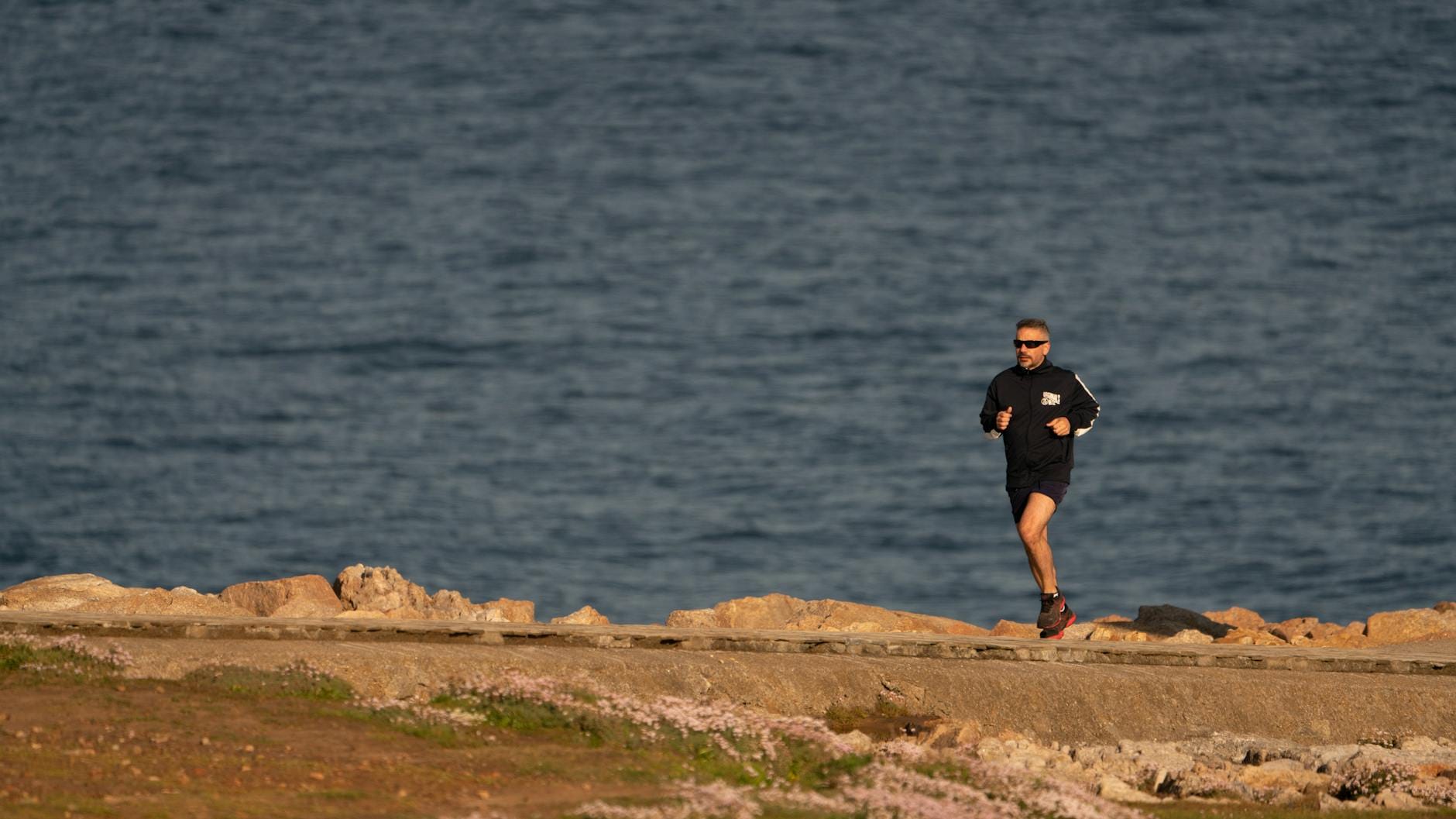 Biegacz na skalistym wybrzeżu z widokiem na morze