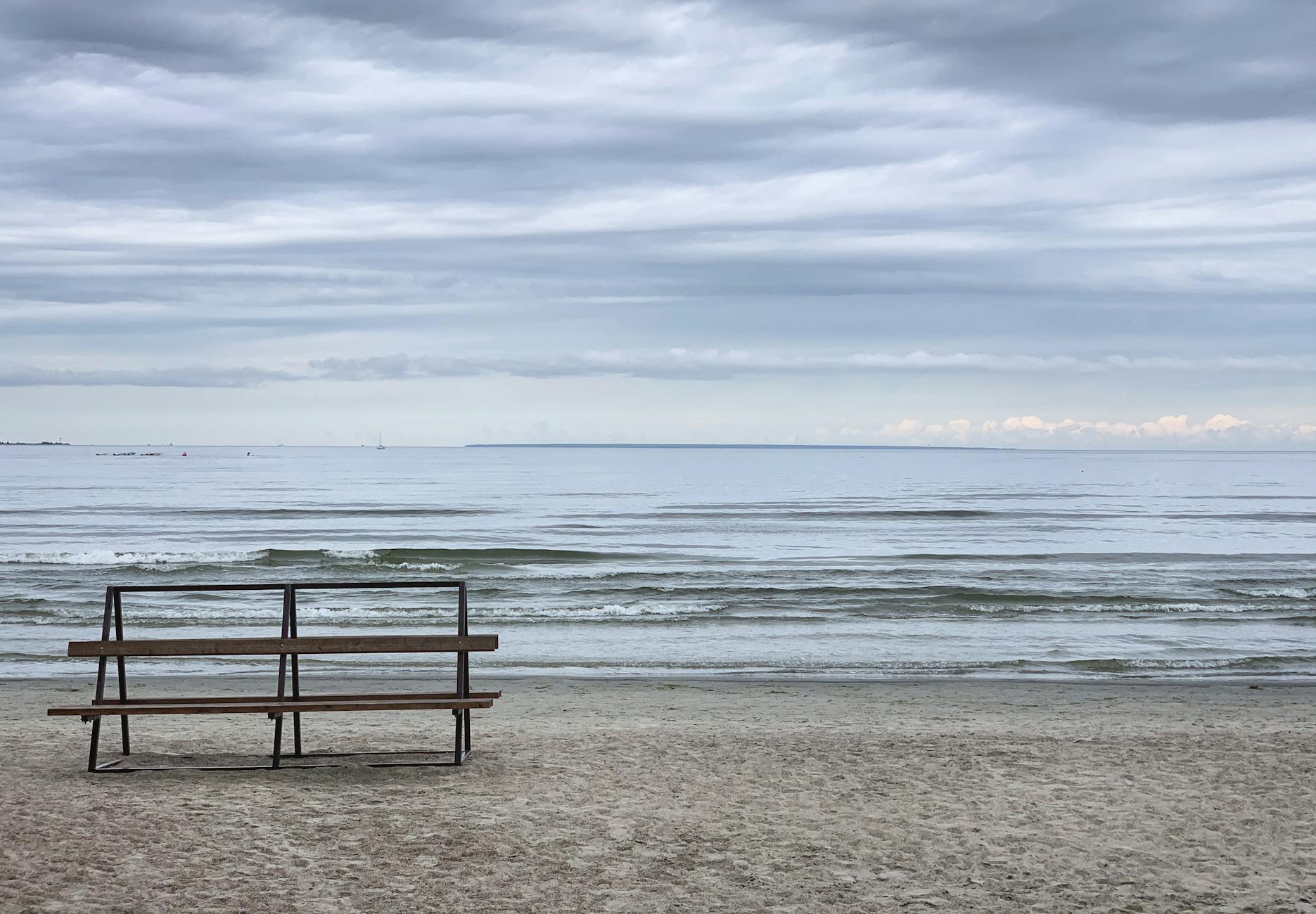 Pusta ławka z widokiem na spokojne morze Bałtyckie pod chmurami